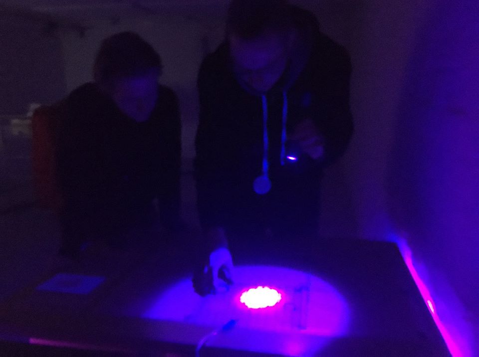 An image of two people solving a puzzle in a dimply lit space.